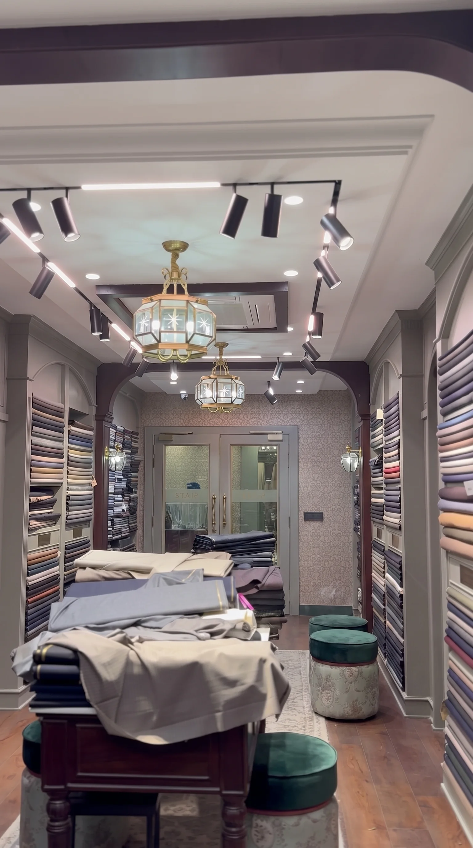 The fabric wall inside Punjab Fabrics — bolts floor to ceiling, brass lanterns above.