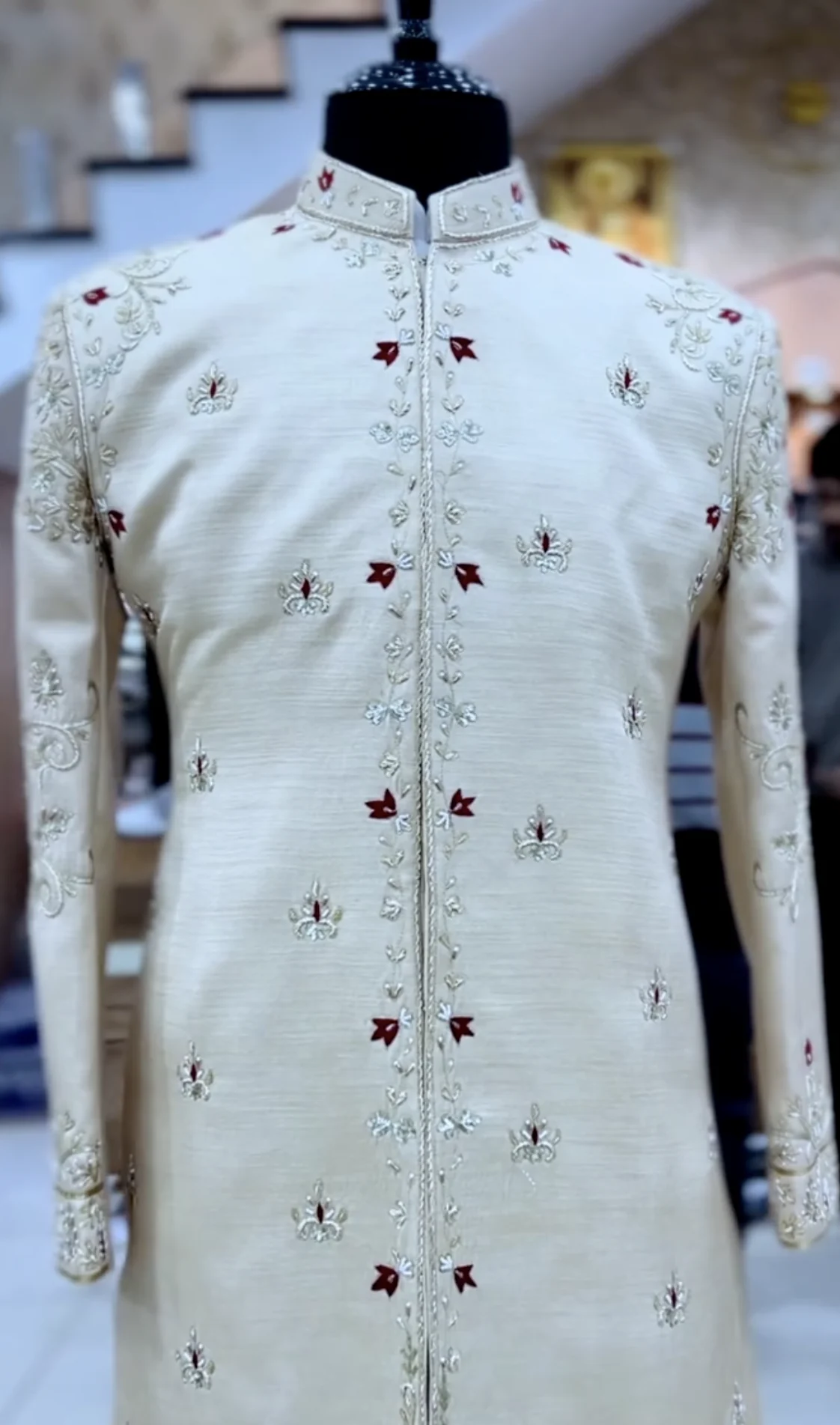 An ivory sherwani with gold and maroon hand-embroidery, on the Punjab Fabrics floor.